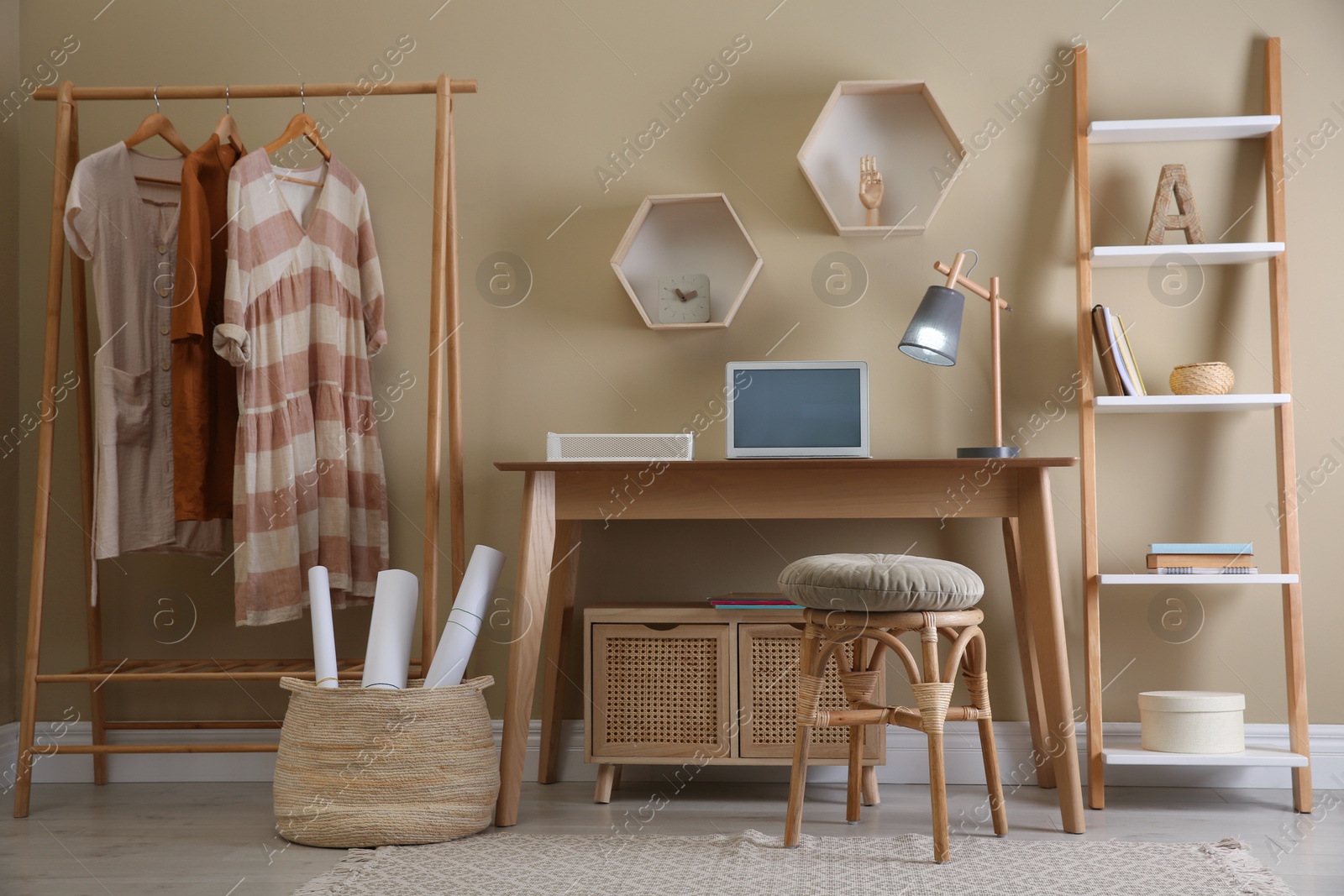 Photo of Comfortable wooden stool near table with laptop indoors. Interior design