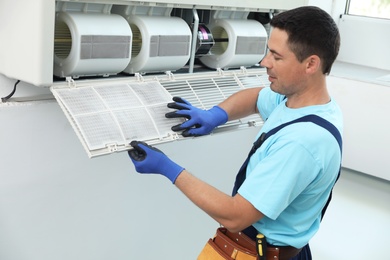 Male technician cleaning air conditioner indoors