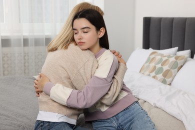 Mother consoling her upset daughter in bedroom. Teenager problems