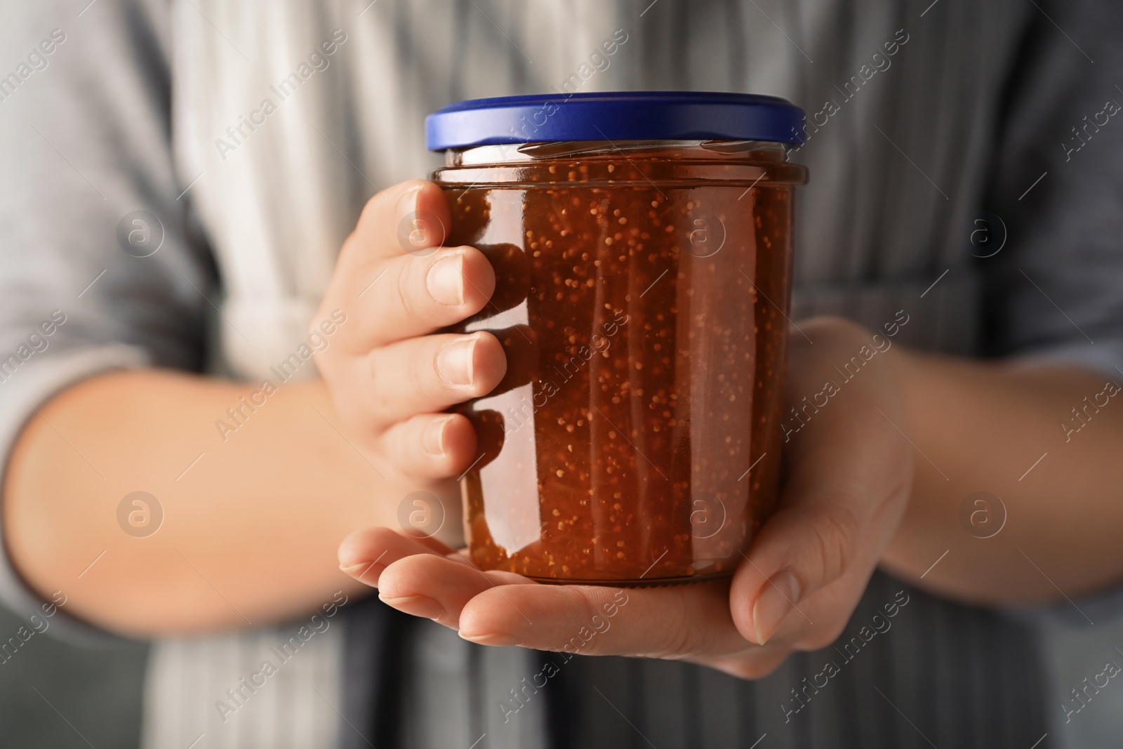 Photo of Woman with jar of fig jam, closeup