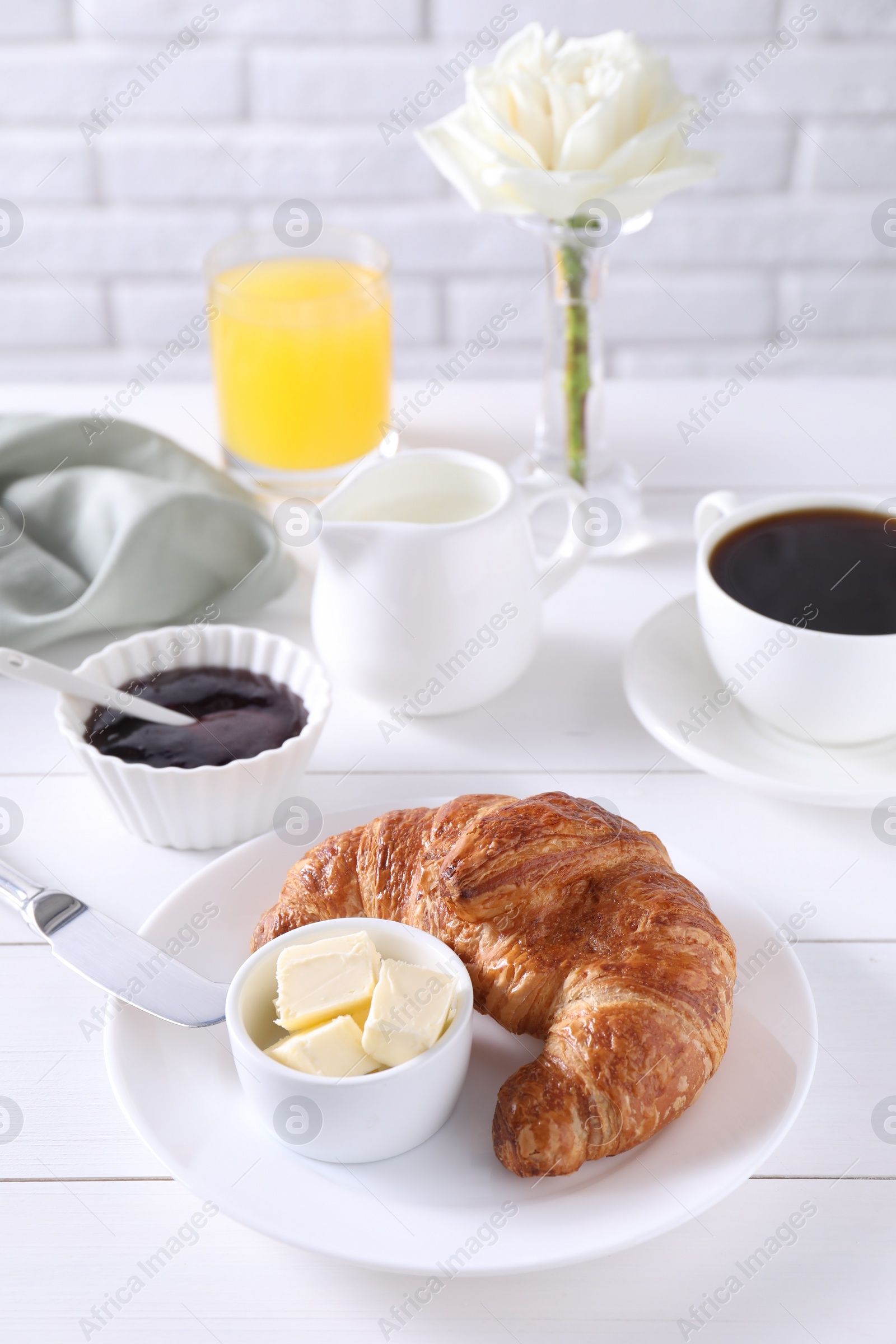 Photo of Fresh croissant, butter, jam and coffee on white wooden table. Tasty breakfast