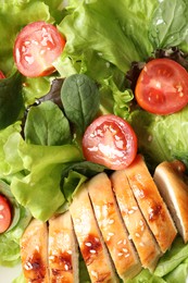 Delicious salad with chicken, cherry tomato and spinach as background, top view