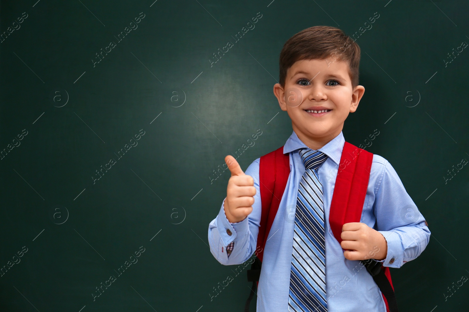 Photo of Cute little child near chalkboard, space for text. First time at school