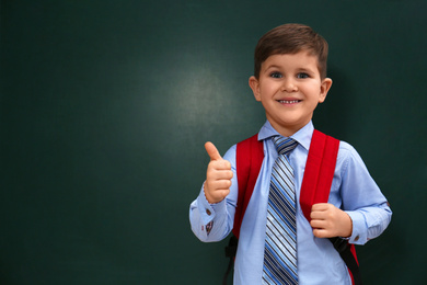 Cute little child near chalkboard, space for text. First time at school