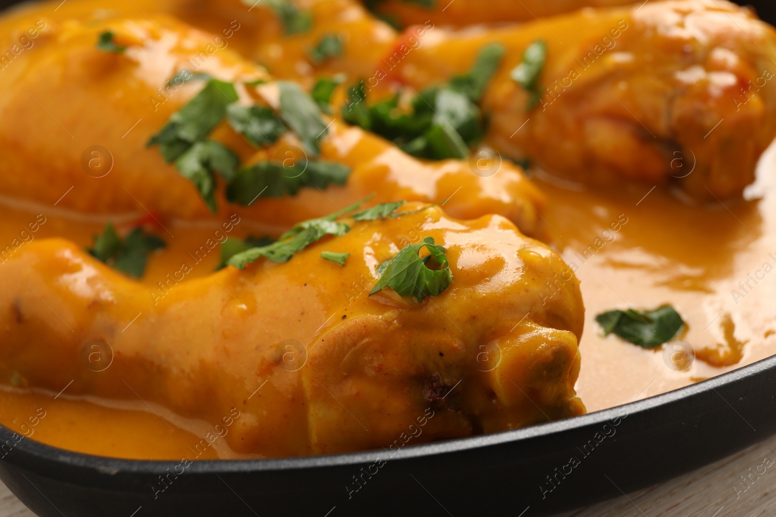 Photo of Tasty chicken curry with parsley on wooden table, closeup
