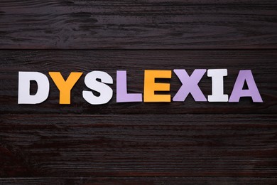Photo of Word Dyslexia made of paper letters on dark wooden table, flat lay