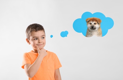 Image of Little boy on light background dreaming about cute puppy