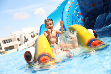Photo of Little boy on slide at water park. Summer vacation