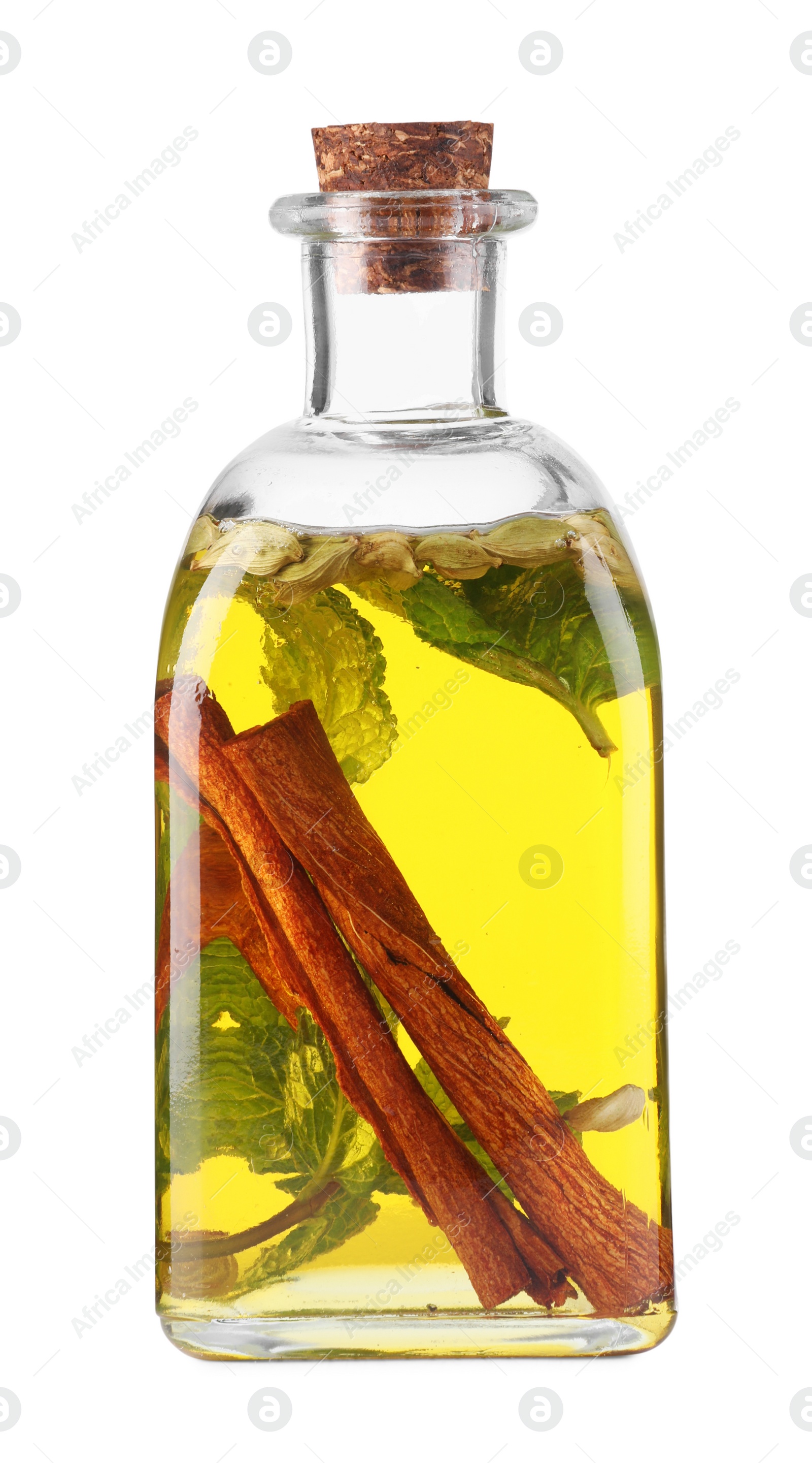 Photo of Glass bottle of cooking oil with spices and herbs isolated on white