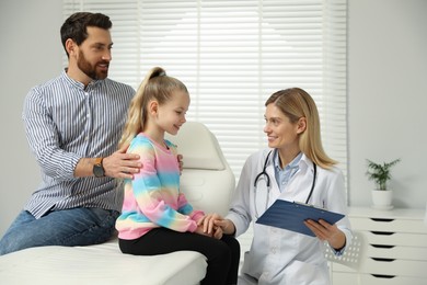 Photo of Father and daughter having appointment with doctor. Pediatrician consulting patient in clinic