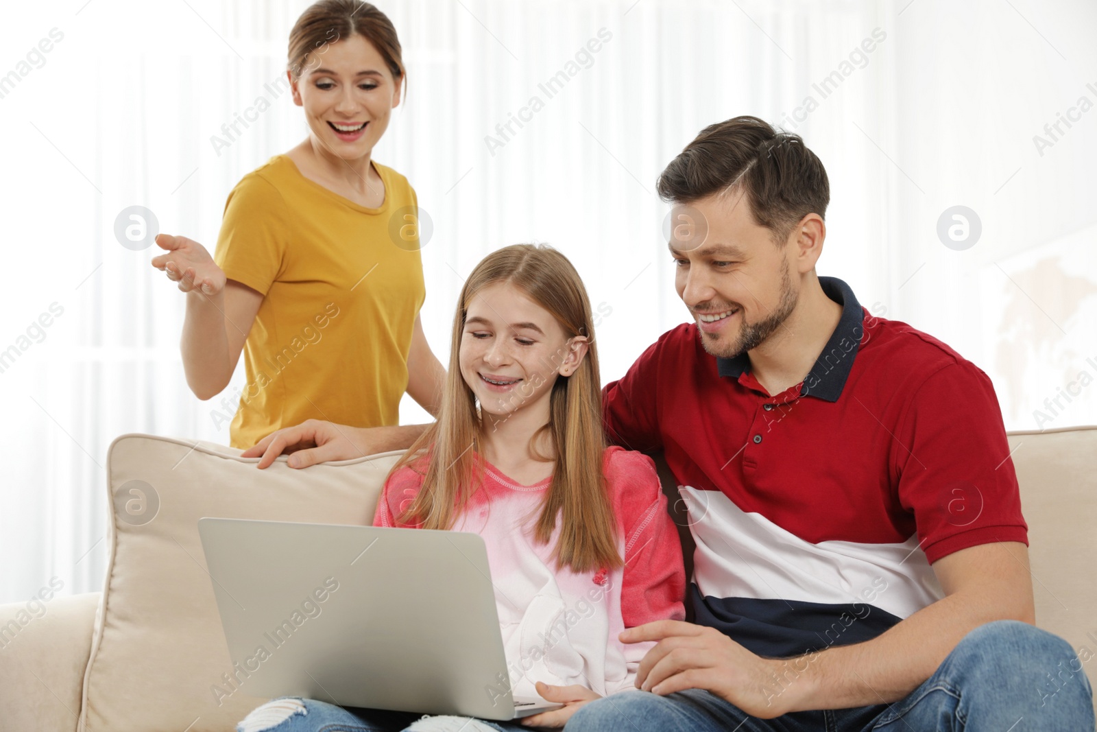 Photo of Parents and their teenager daughter with laptop computer at home