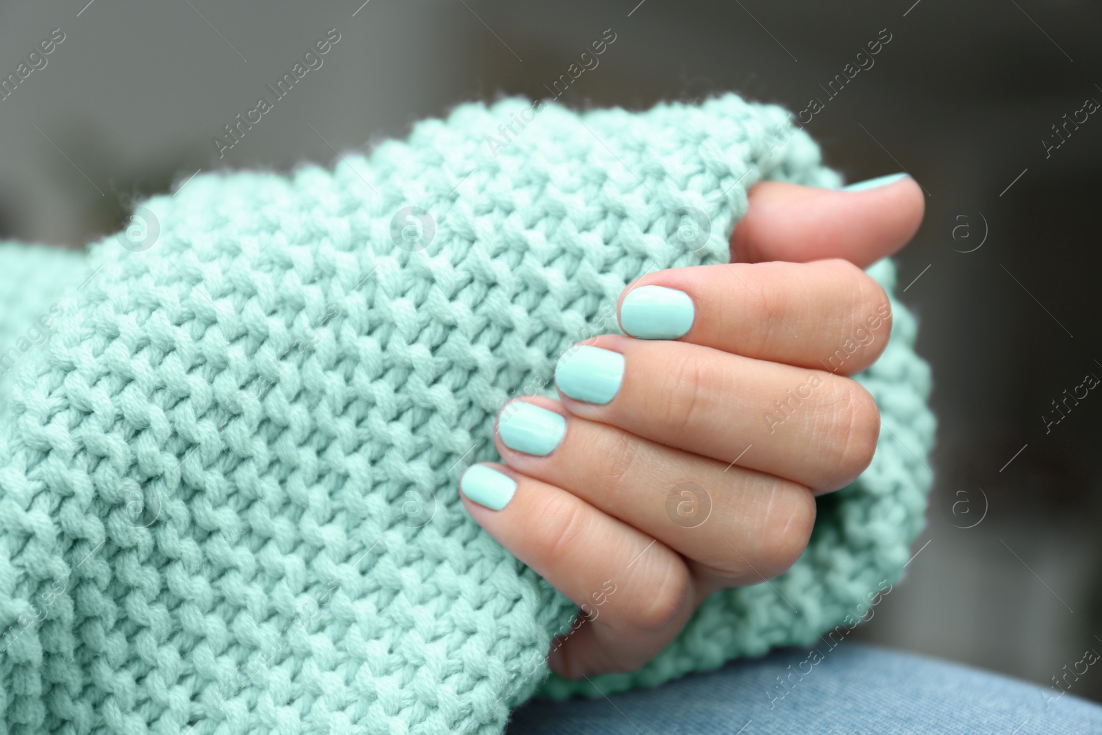 Photo of Young woman with stylish mint manicure and knitted plaid, closeup