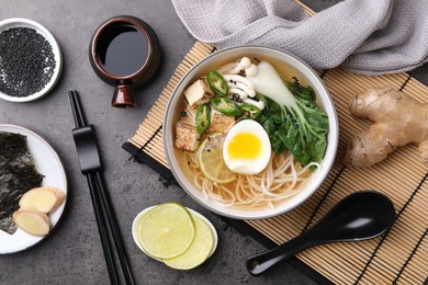 Photo of Vegetarian ramen and ingredients on grey table, flat lay