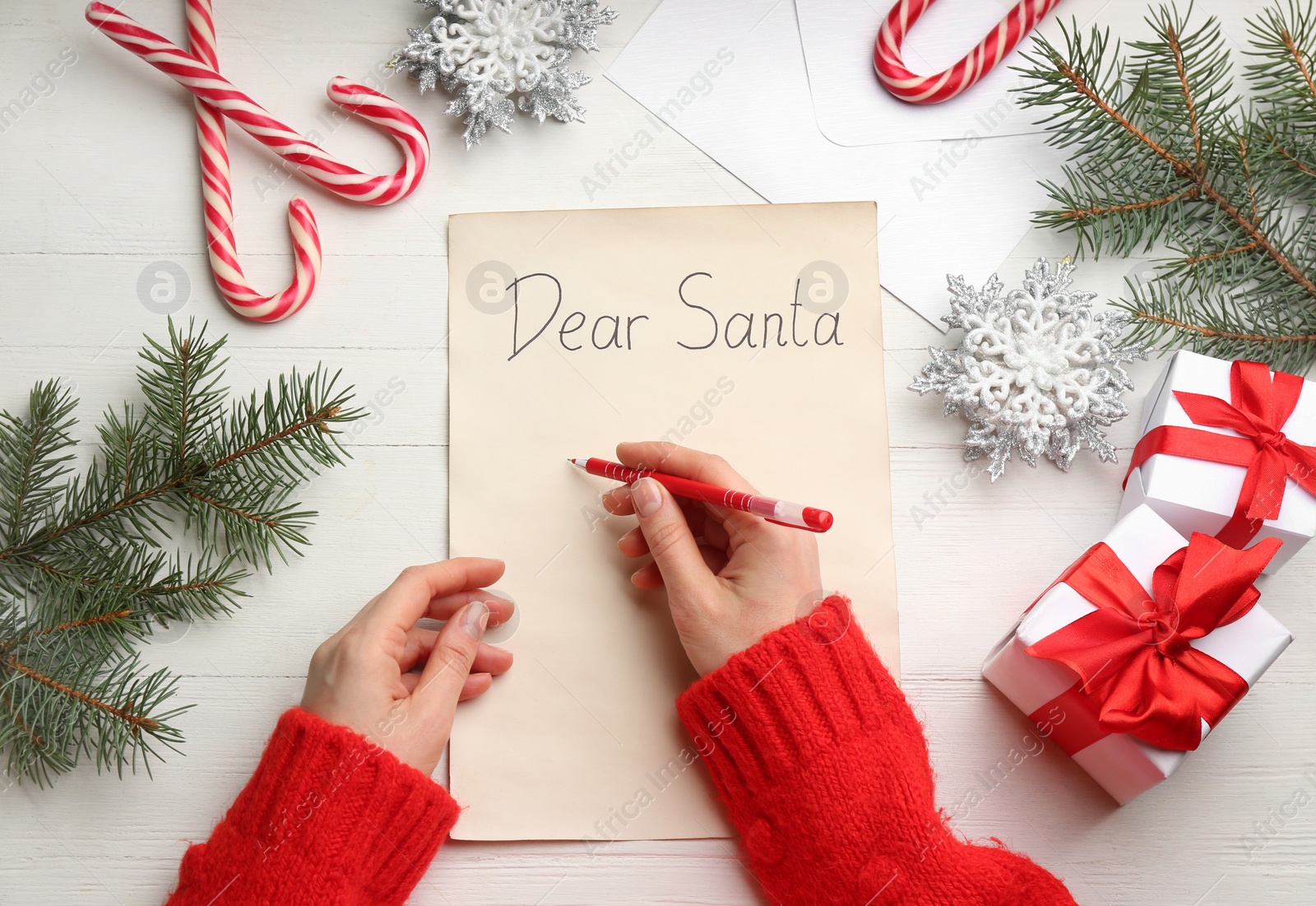 Photo of Woman writing letter to Santa at white wooden table, top view