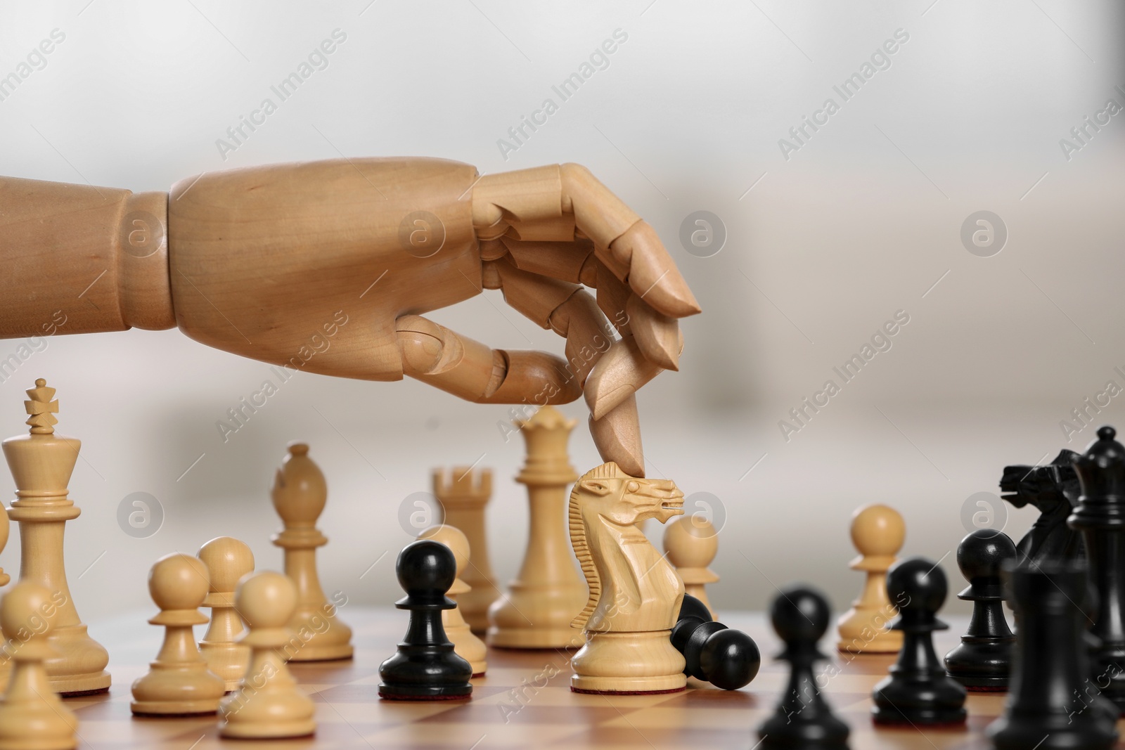 Photo of Robot moving chess piece on board against light background, closeup. Wooden hand representing artificial intelligence