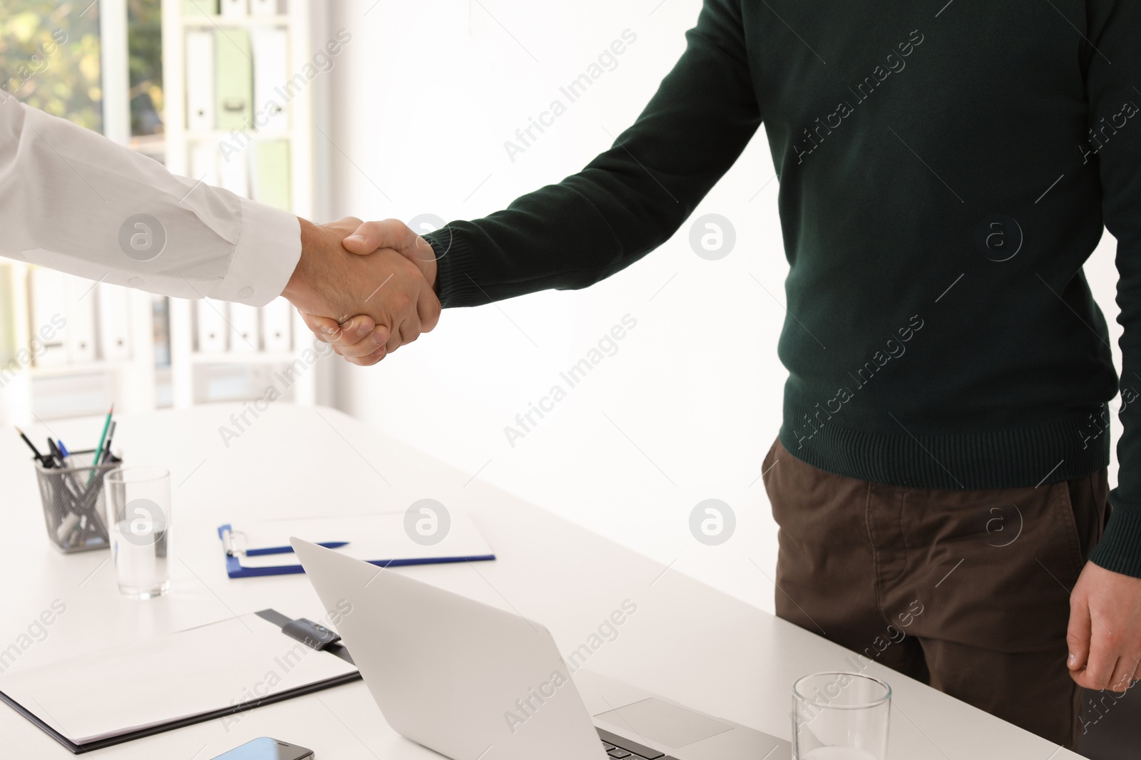 Photo of Human resources manager shaking hands with applicant during job interview in office