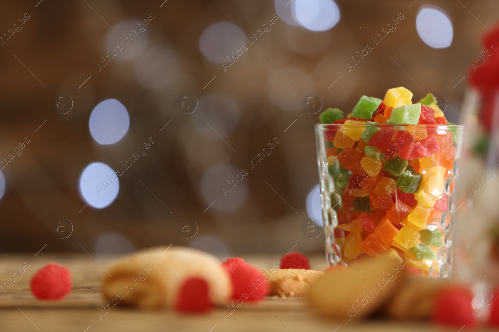 Photo of Delicious candies in glass on table against blurred background, space for text