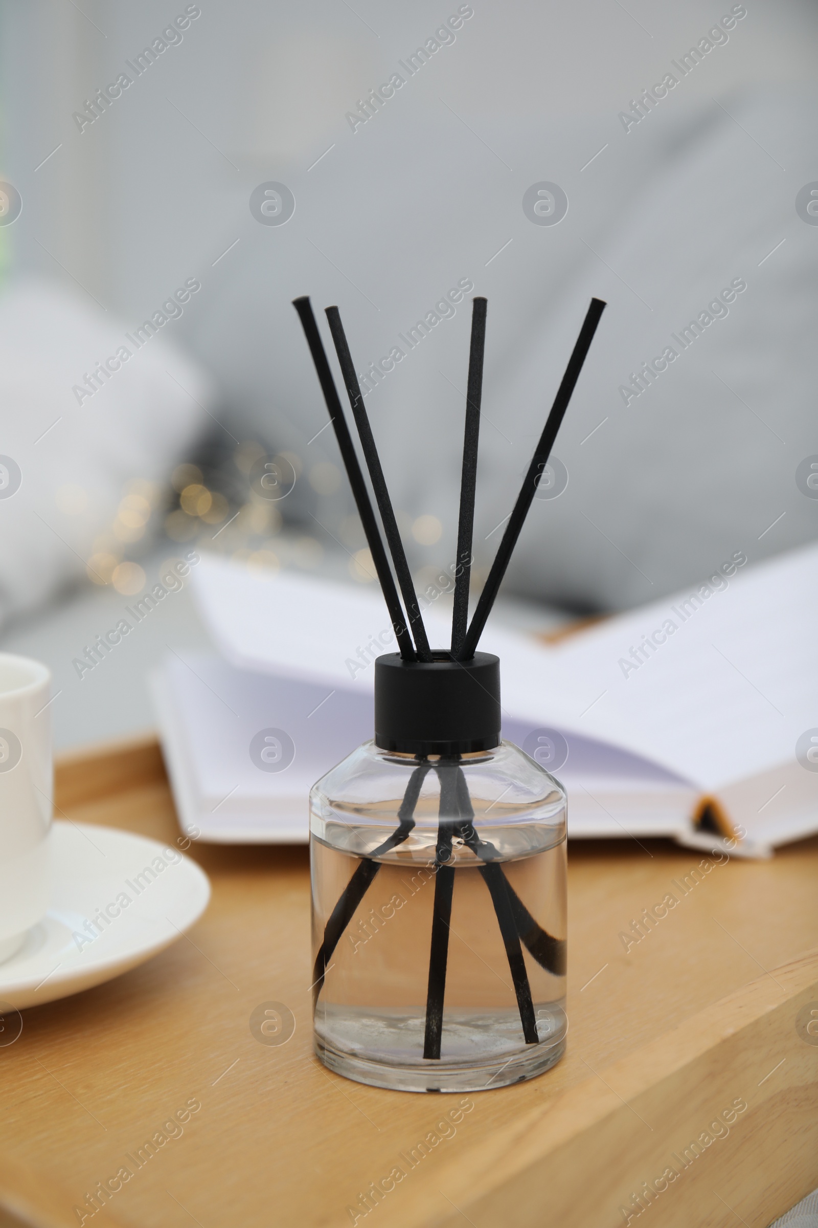 Photo of Aromatic reed air freshener on wooden tray in bedroom