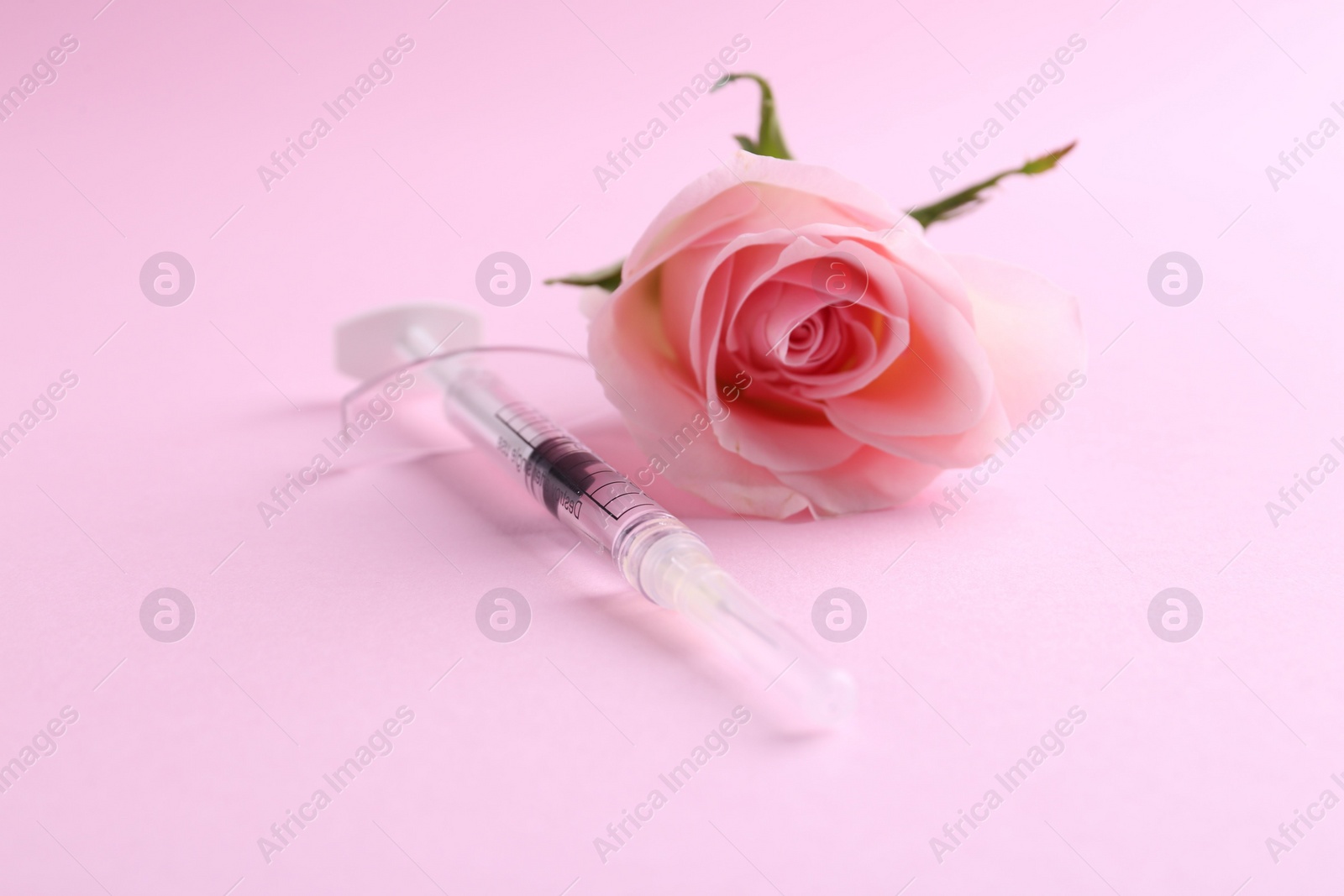 Photo of Cosmetology. Medical syringe and rose flower on pink background, closeup