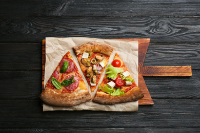 Photo of Slices of different delicious pizzas on black wooden table, top view