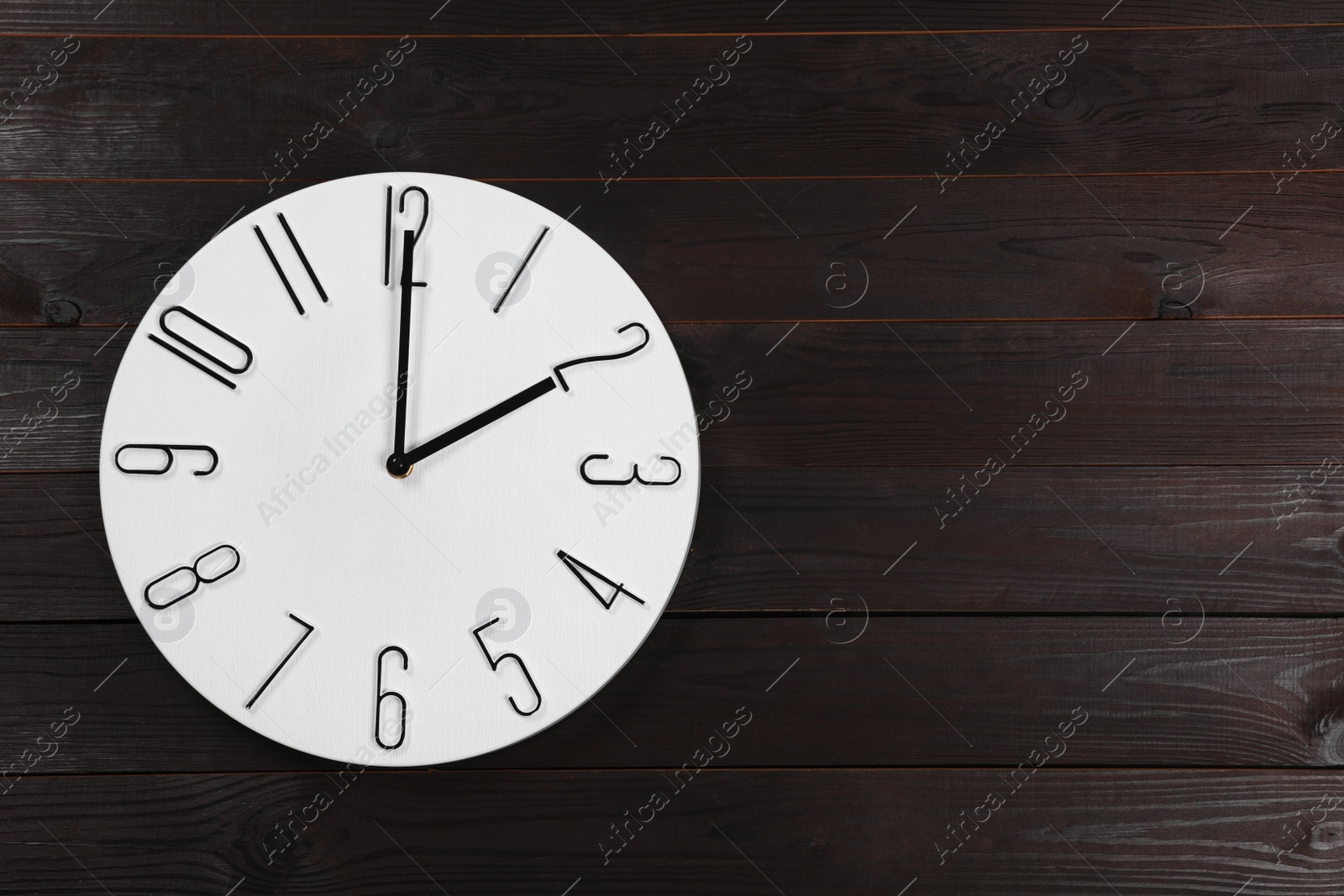Photo of Stylish analog clock hanging on wooden wall, space for text