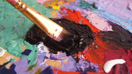 Photo of Applying colorful oil paints with brush on canvas, closeup