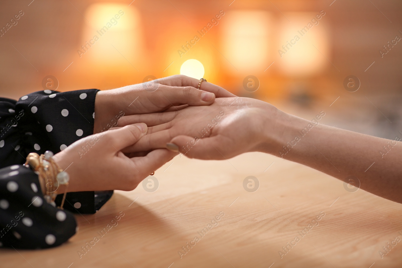 Photo of Chiromancer reading lines on woman's palm at table, closeup