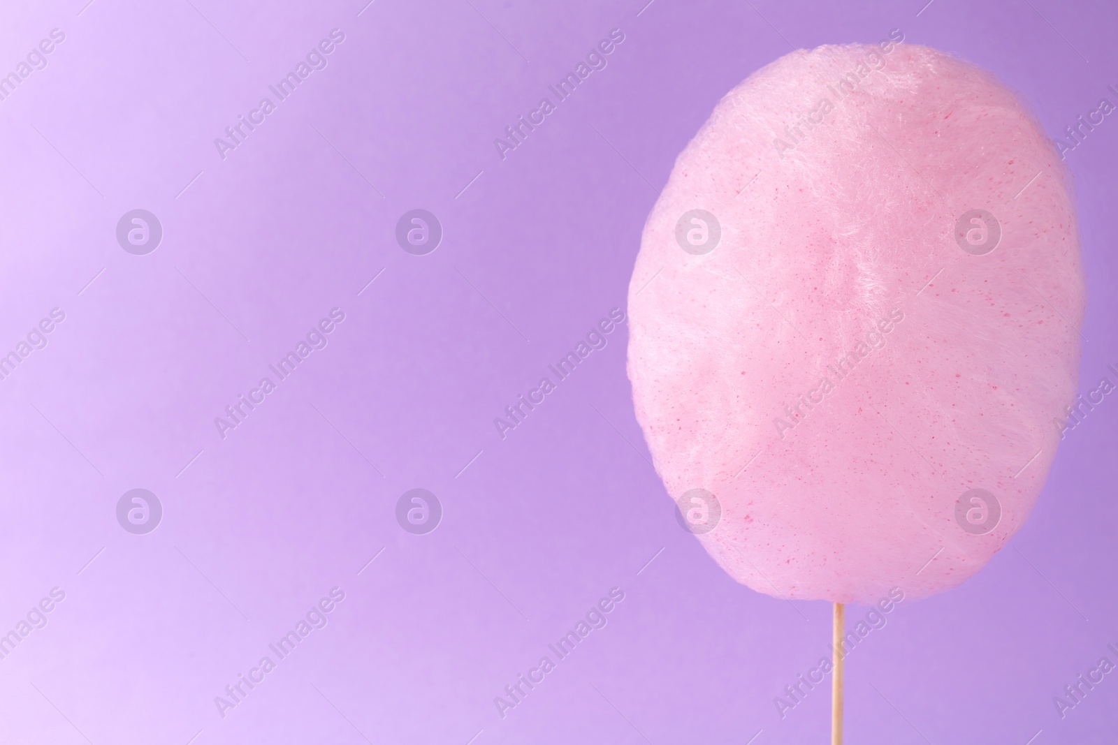Photo of Sweet cotton candy on violet background, space for text