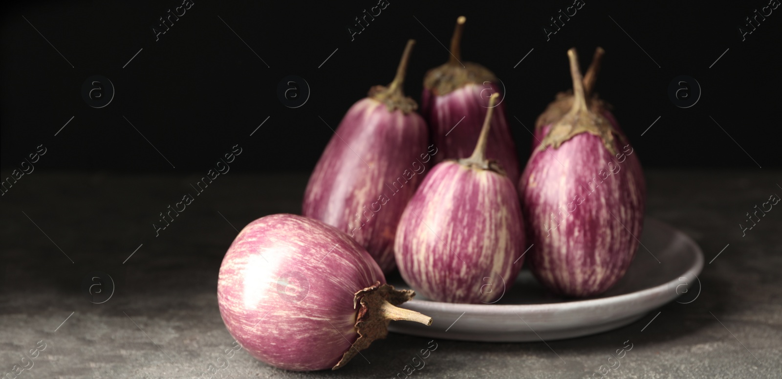 Image of Ripe purple eggplants on grey table, closeup. Banner design