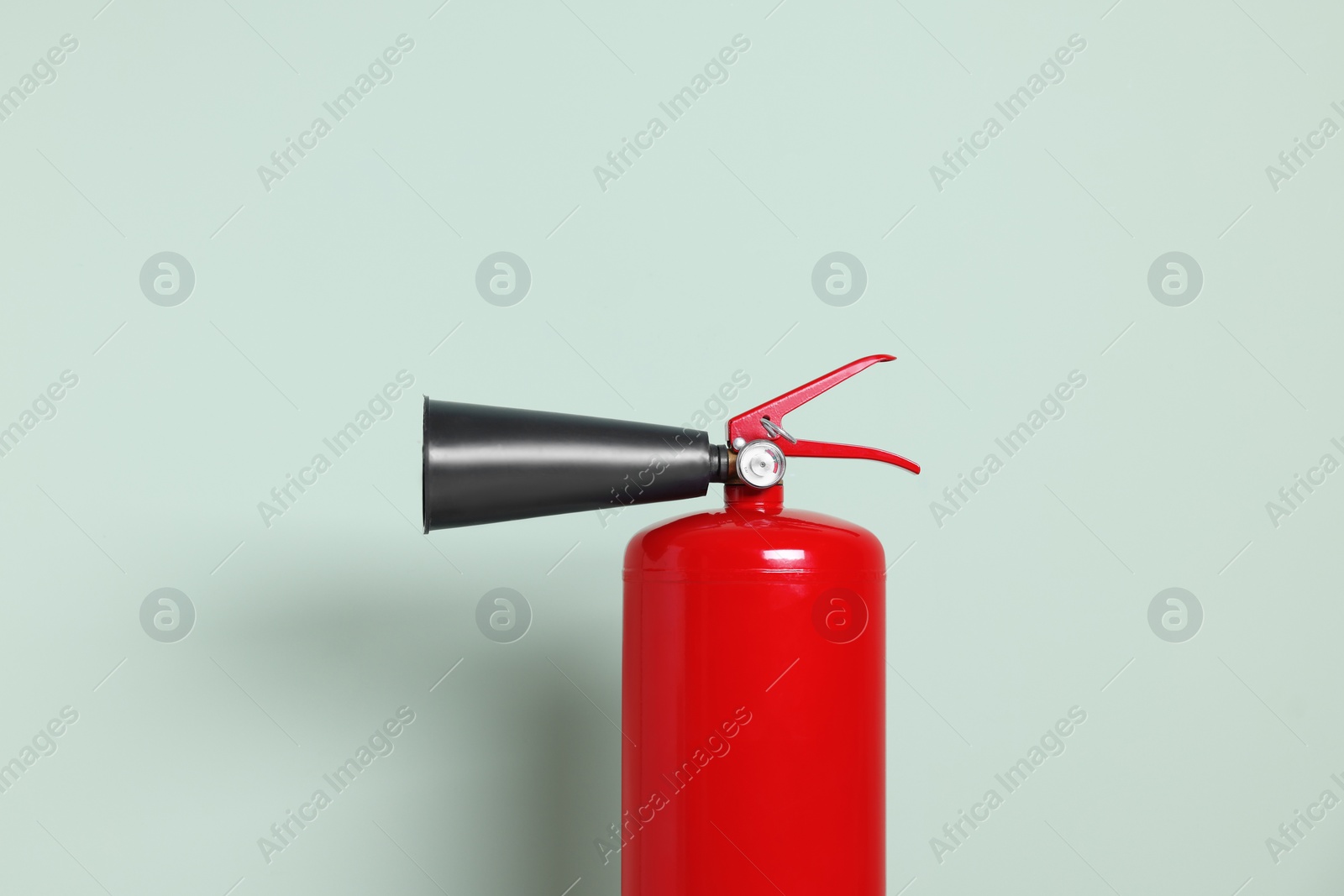 Photo of Red fire extinguisher against light green background