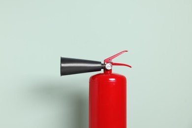 Photo of Red fire extinguisher against light green background
