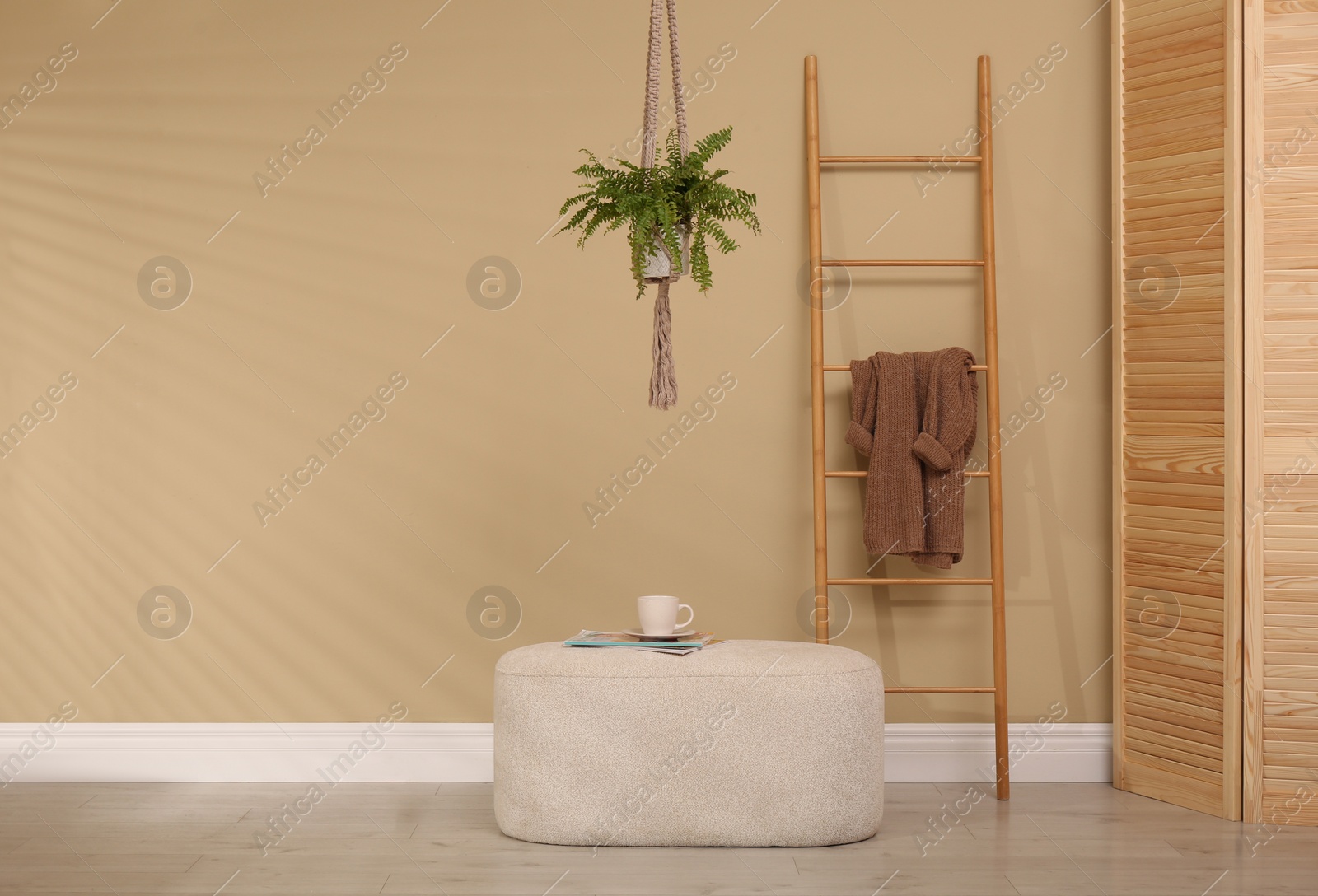 Photo of Stylish room interior with comfortable pouf and ladder near beige wall