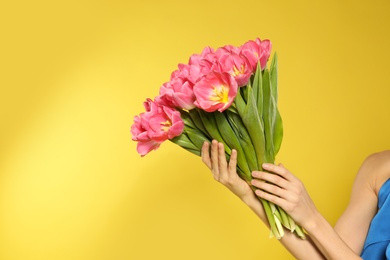 Photo of Girl with spring tulips on yellow background, space for text. International Women's Day