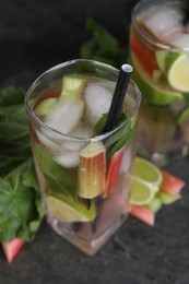 Photo of Tasty rhubarb cocktail with lime on black table, closeup