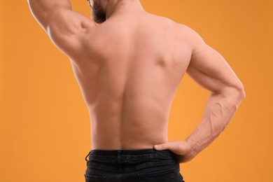 Photo of Muscular man on orange background, closeup. Sexy body