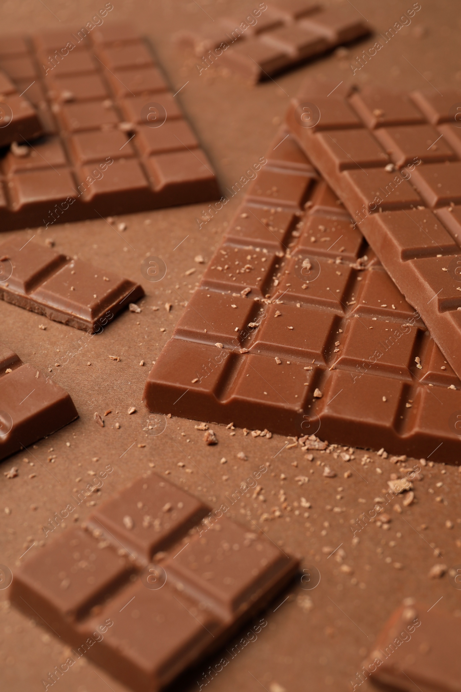 Photo of Pieces of tasty chocolate on brown background