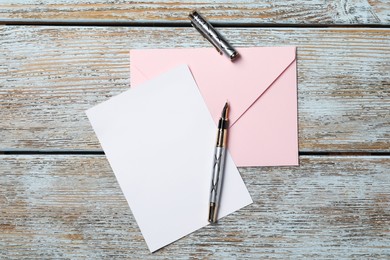 Photo of Blank sheet of paper, pen and letter envelope on wooden rustic table, top view. Space for text