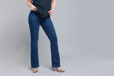 Woman in stylish jeans on grey background, closeup. Space for text