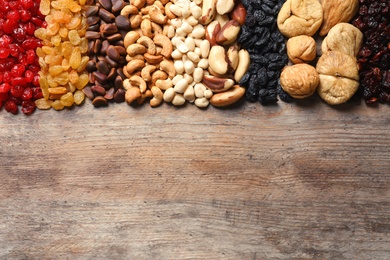 Different dried fruits and nuts on wooden background, top view. Space for text