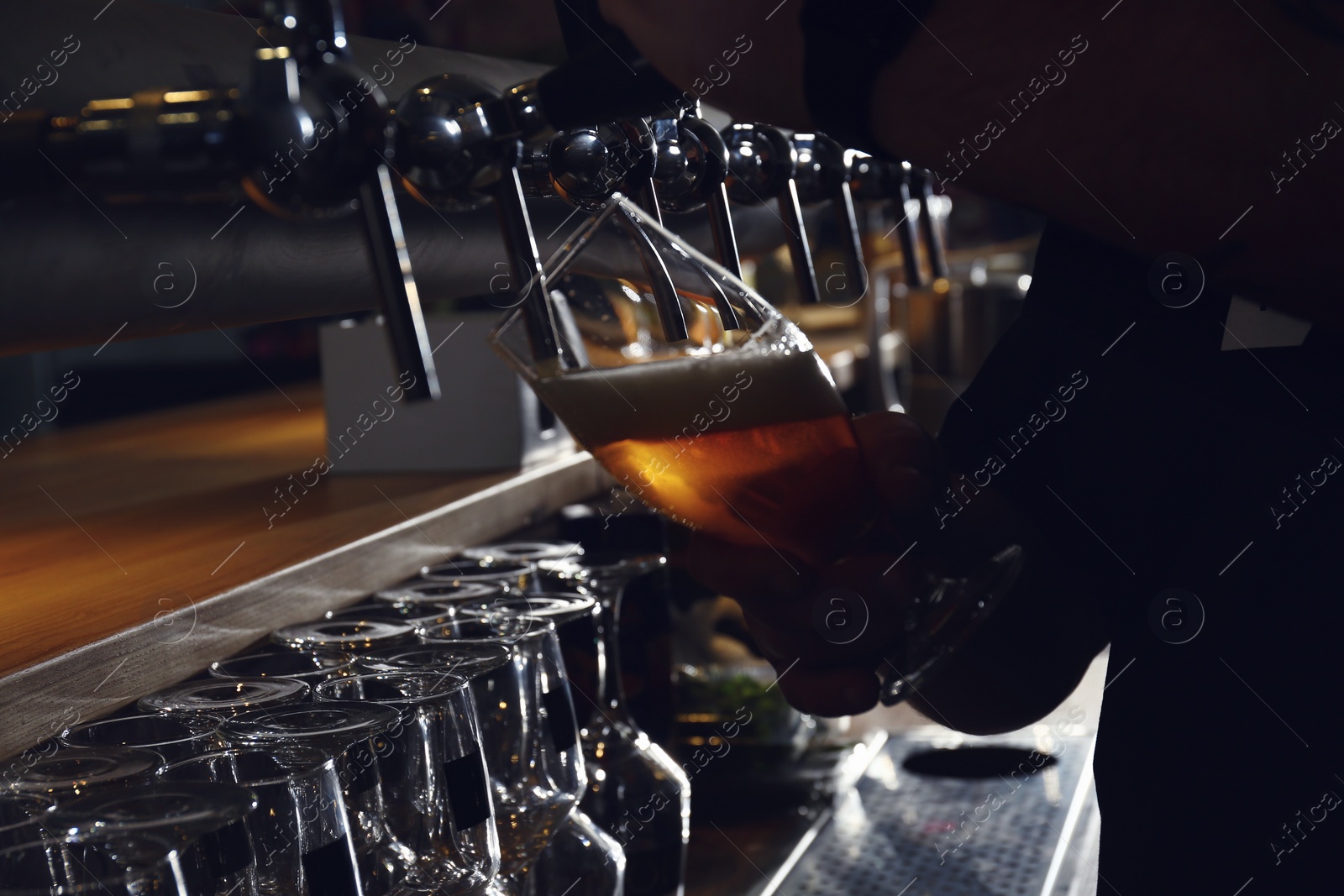 Photo of Bartender pouring beer into glass in pub, closeup