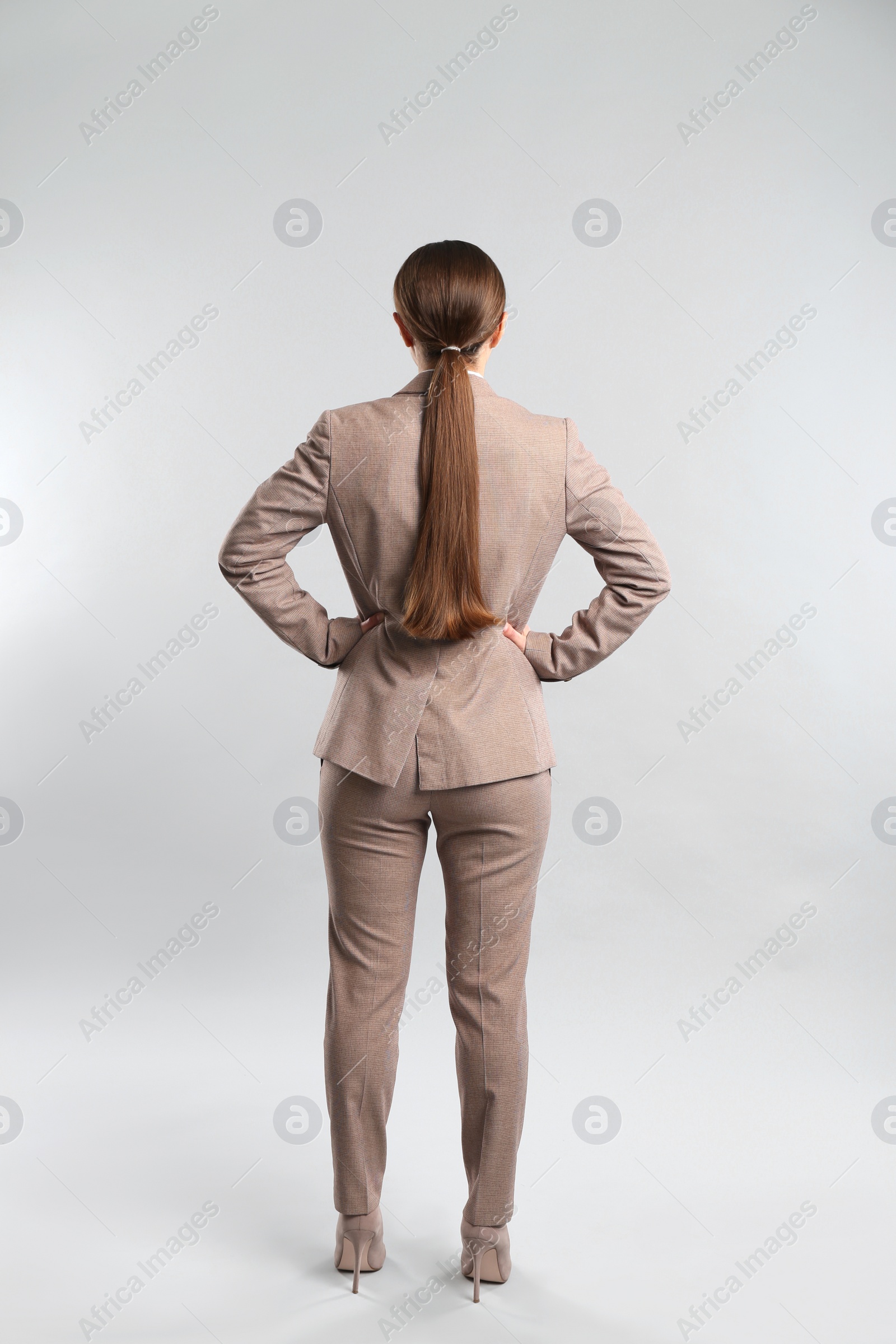 Photo of Young woman on grey background, back view