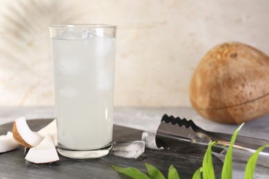 Photo of Glass of coconut water, ice cubes and nuts on grey table