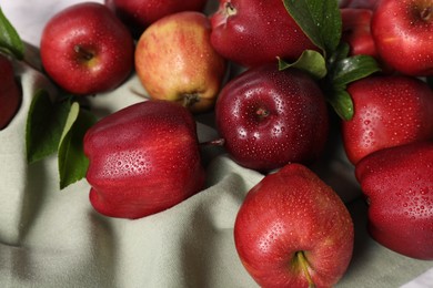 Photo of Ripe red apples with leaves and water drops on table