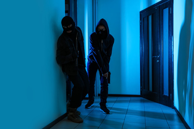 Dangerous criminals with gun and crow bar in hallway