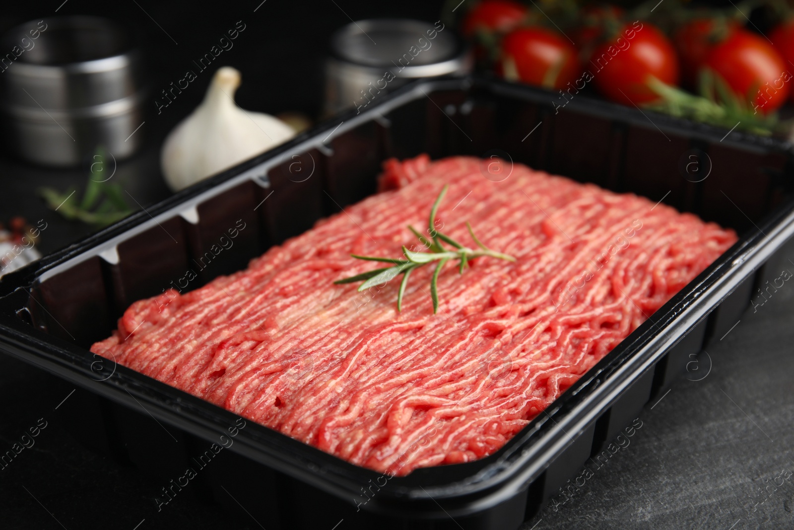 Photo of Plastic container with fresh minced meat on black table, closeup