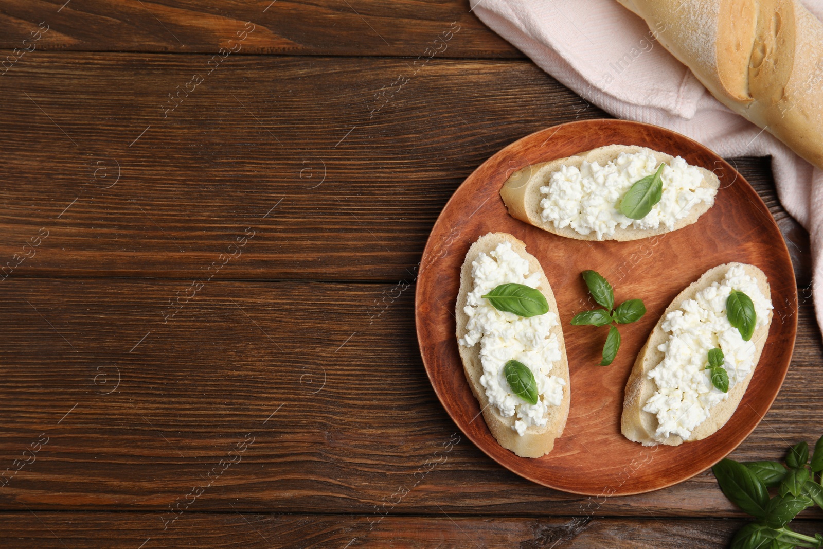 Photo of Bread with cottage cheese and basil on wooden table, flat lay. Space for text