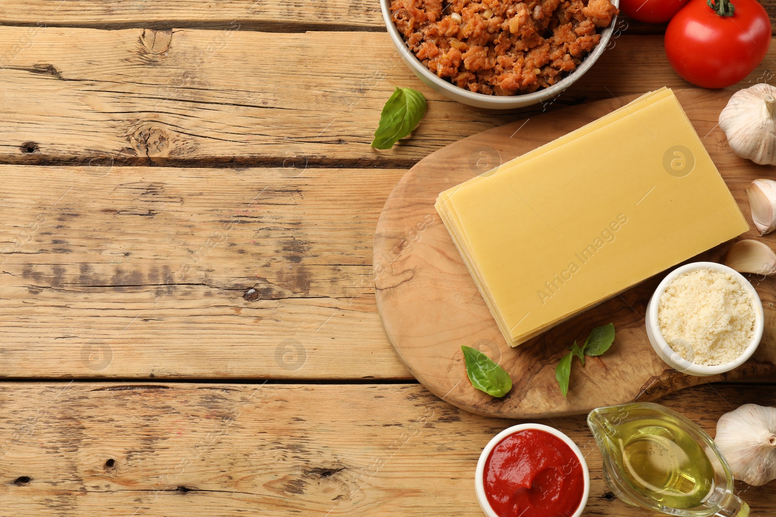 Photo of Flat lay composition with products for cooking lasagna on wooden table. Space for text