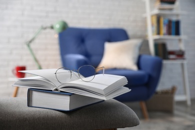 Books with glasses on bench in room