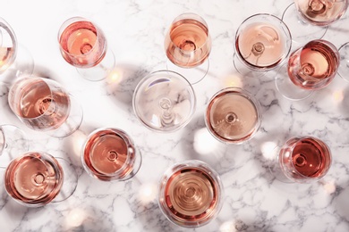 Different glasses with rose wine on marble background, flat lay