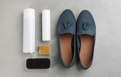 Stylish footwear with shoe care accessories on light grey stone table, flat lay